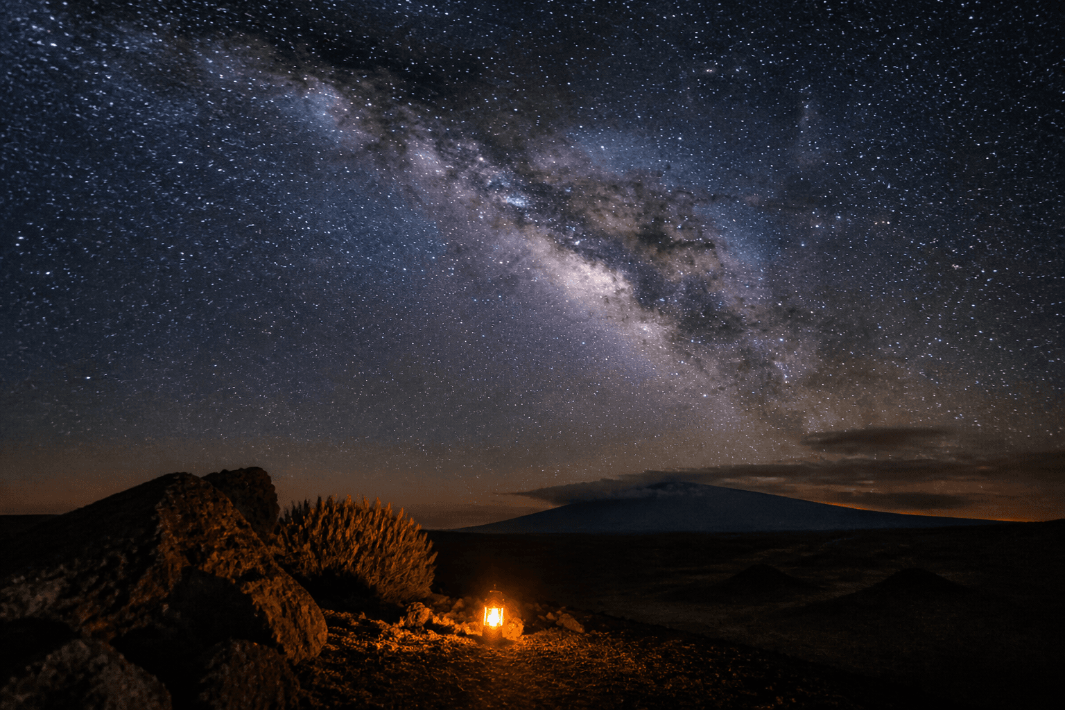 Synthetic Milky Way view above a dark volcanic landscape on Hawaii Island.